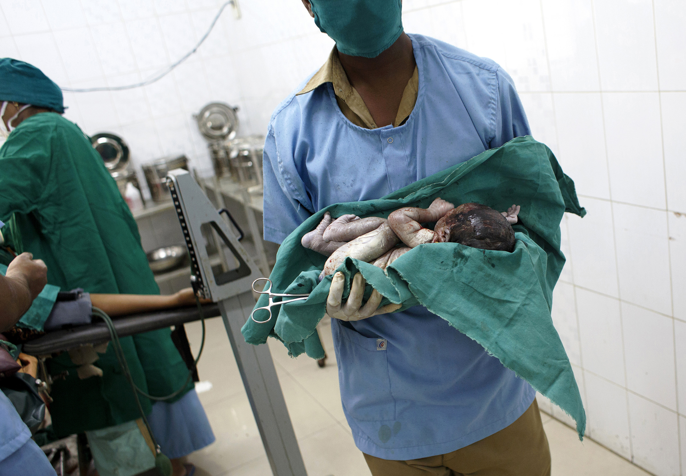 A newborn, seconds after delivery, is carried to the neonatal area in the Medavakkam Primary Health Centre in Tamil Nadu. The Centre delivers 150 to 200 babies a month, and Dr. Ravichandran, the director, estimates that over 90 percent of women from the surrounding area now give birth at the hospital rather than at home. In Tamil Nadu, maternal and family health care have been part of the governmentÕs longstanding investment in public health. SARAH WEISER