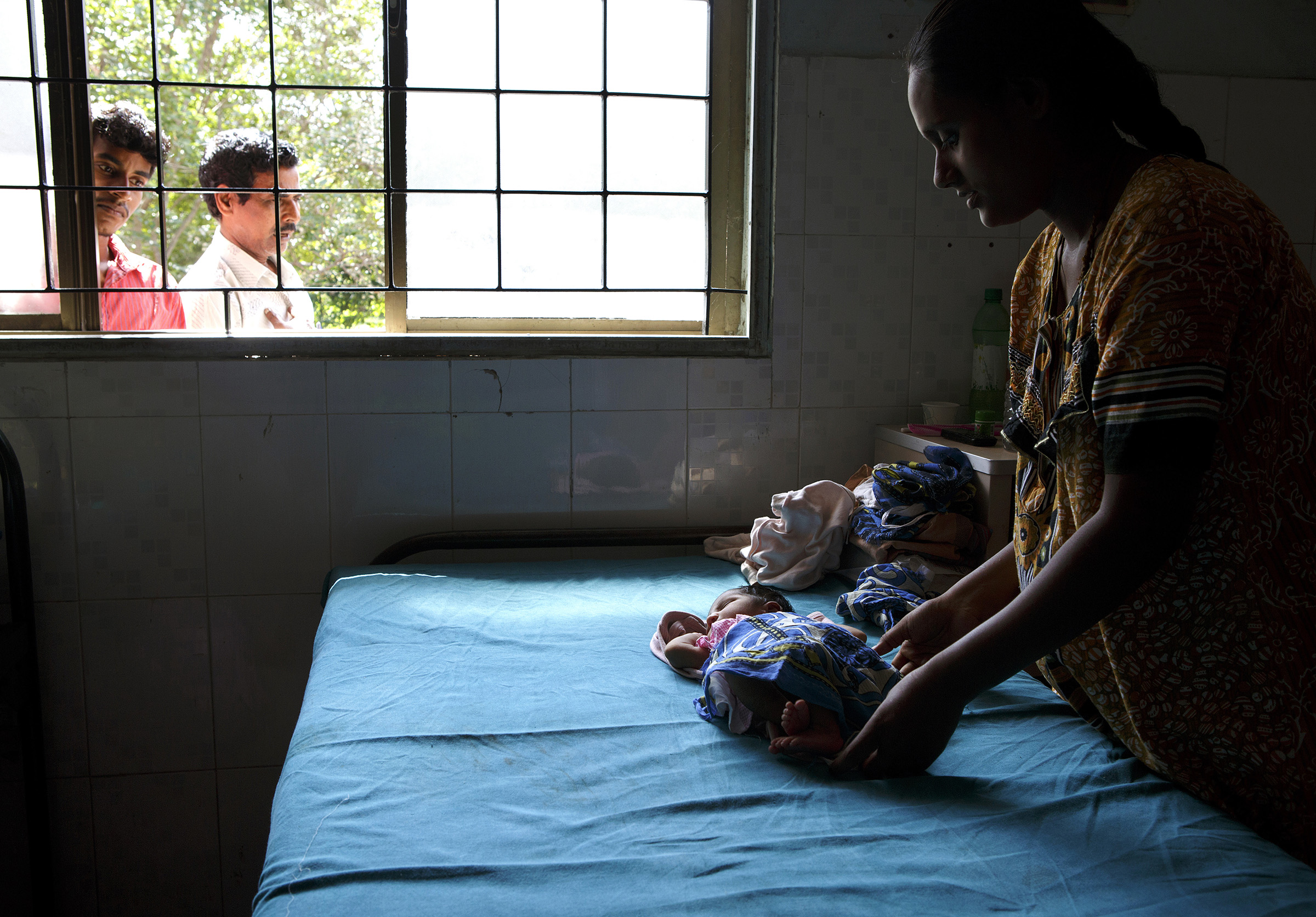 B. Rajeshwari, 23, cares for her first child, a 5-day-old daughter not yet named, at the Medavakkam Primary Health Centre in Tamil Nadu. A family friend, Radish, far left, looks on. SARAH WEISER