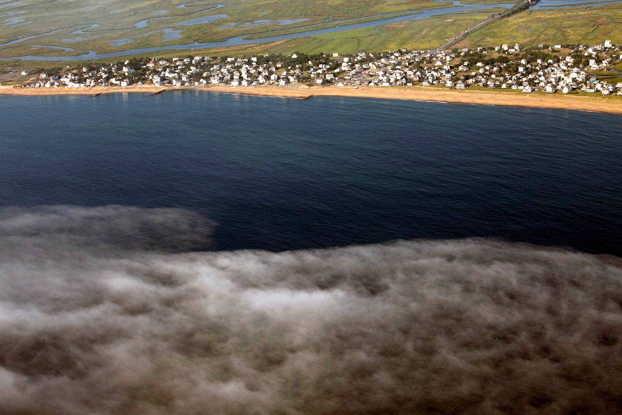 Homes and businesses on Plum Island come face-to-face with the Atlantic Ocean. “The big problem with climate change and sea level rise is that it’s a slow motion disaster and people don’t really perceive that it’s happening,” says Mike Morris of Storm Surge, a nonprofit organization in nearby Newburyport that helps communities prepare for the effects of climate change. (Photo by Lauren Owens Lambert/GroundTruth)