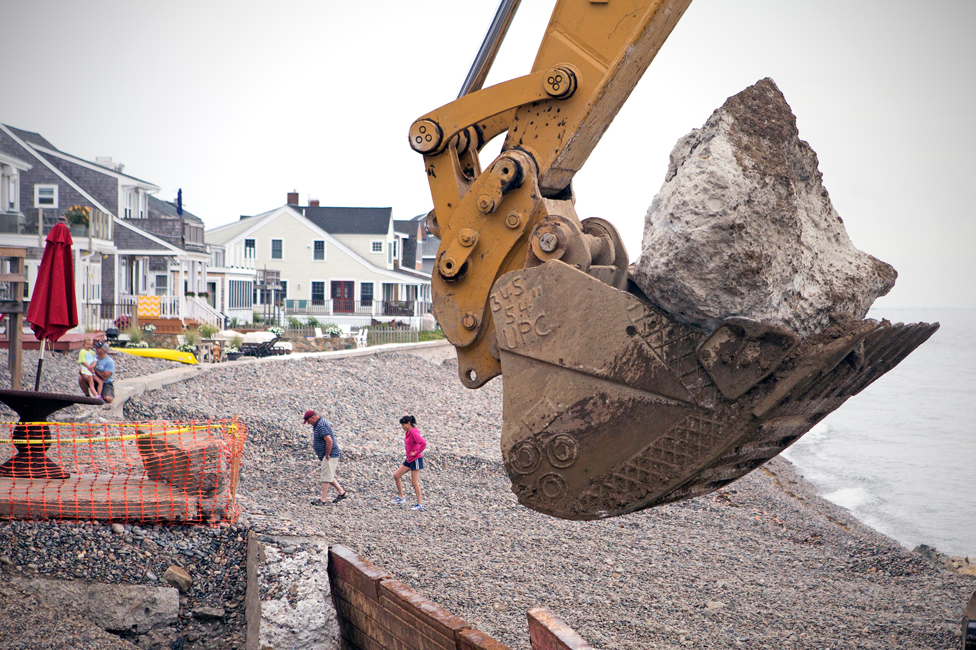 Scituate residents walk along the shore just south of Egypt Beach in Scituate as workers replace the aging seawall. Recent studies estimate that the sea level could rise in New England by 2 to 7 feet by the end of the century – a result of climate change that would drive more storms and flooding and put thousands of homes and businesses at risk. (Photo by Lauren Owens Lambert/GroundTruth)