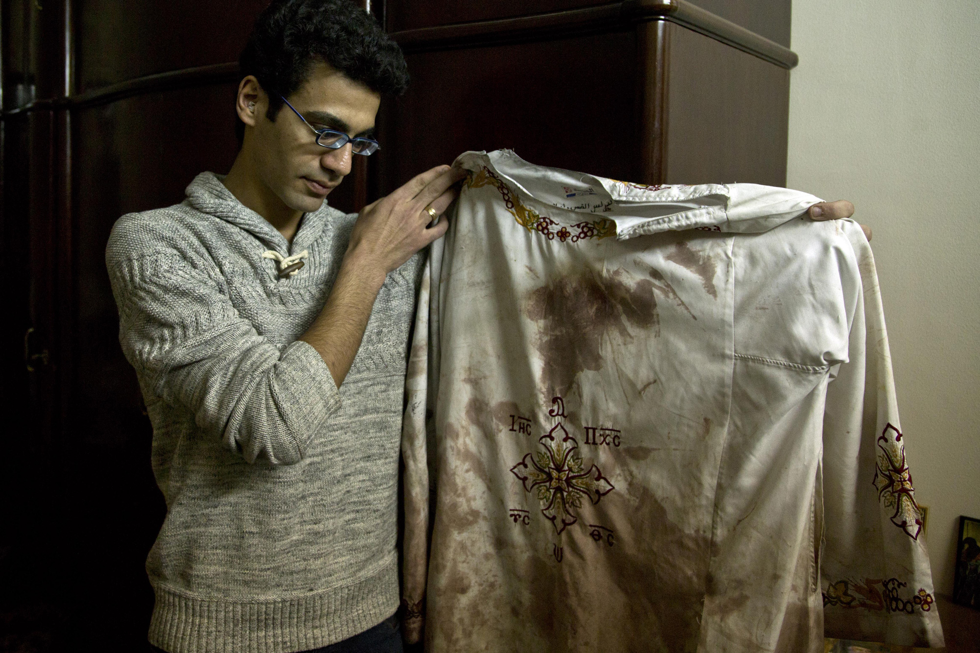 Kirollos is the brother of Bishoy Danial who died in the Palm Sunday suicide bombing in Tanta. He is holding the vestment his father, Priest Daniel, wore during the attack. Tanta, Egypt, April 12, 2017 (Photo by Roger Anis/GroundTruth)