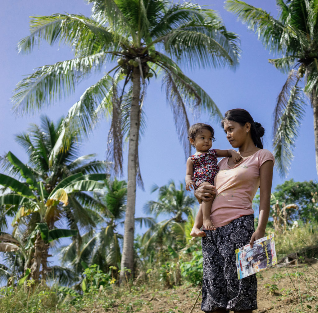 A mother holds her baby in the Philippines, where climate change is driving waves of human trafficking. Click on the photo to see the story. (Photo by Hannah Reyes Morales/GroundTruth)