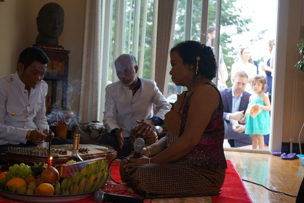 Sovann Khon and his band perform at a Cambodian American wedding in the suburbs of Boston. Curious guests listen from the back porch. (Photo by Heidi Shin)