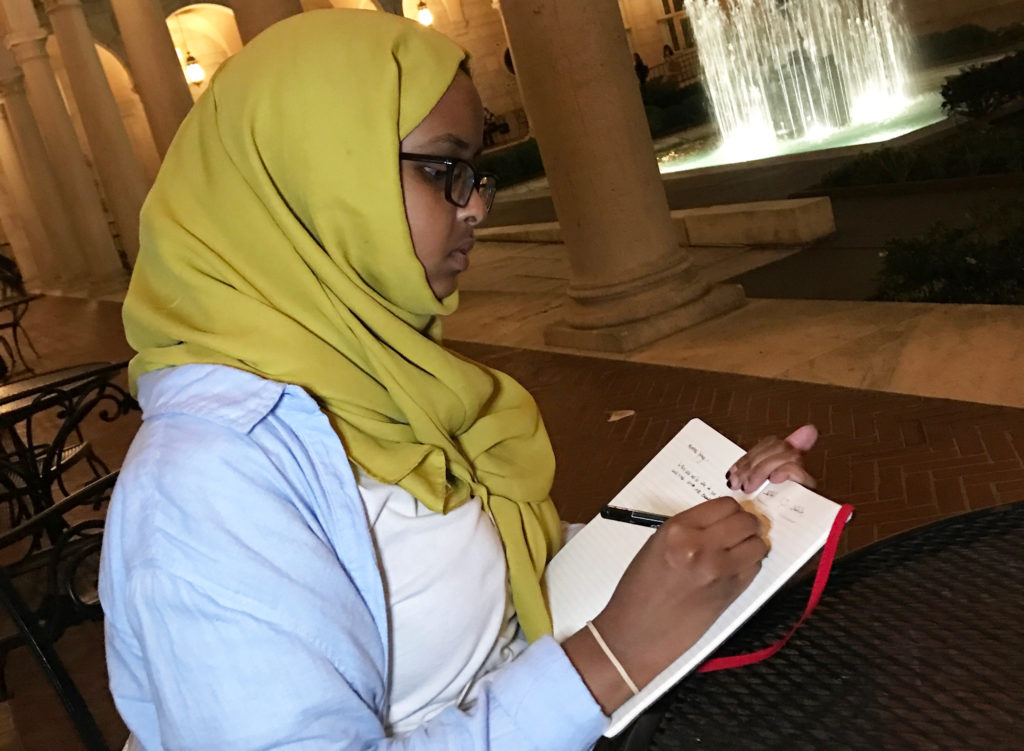 Hamdi Mohamed works on a poem at the Boston Public Library. She and Amal began writing together when they were in middle school. (Photo courtesy of Amal Hussein)