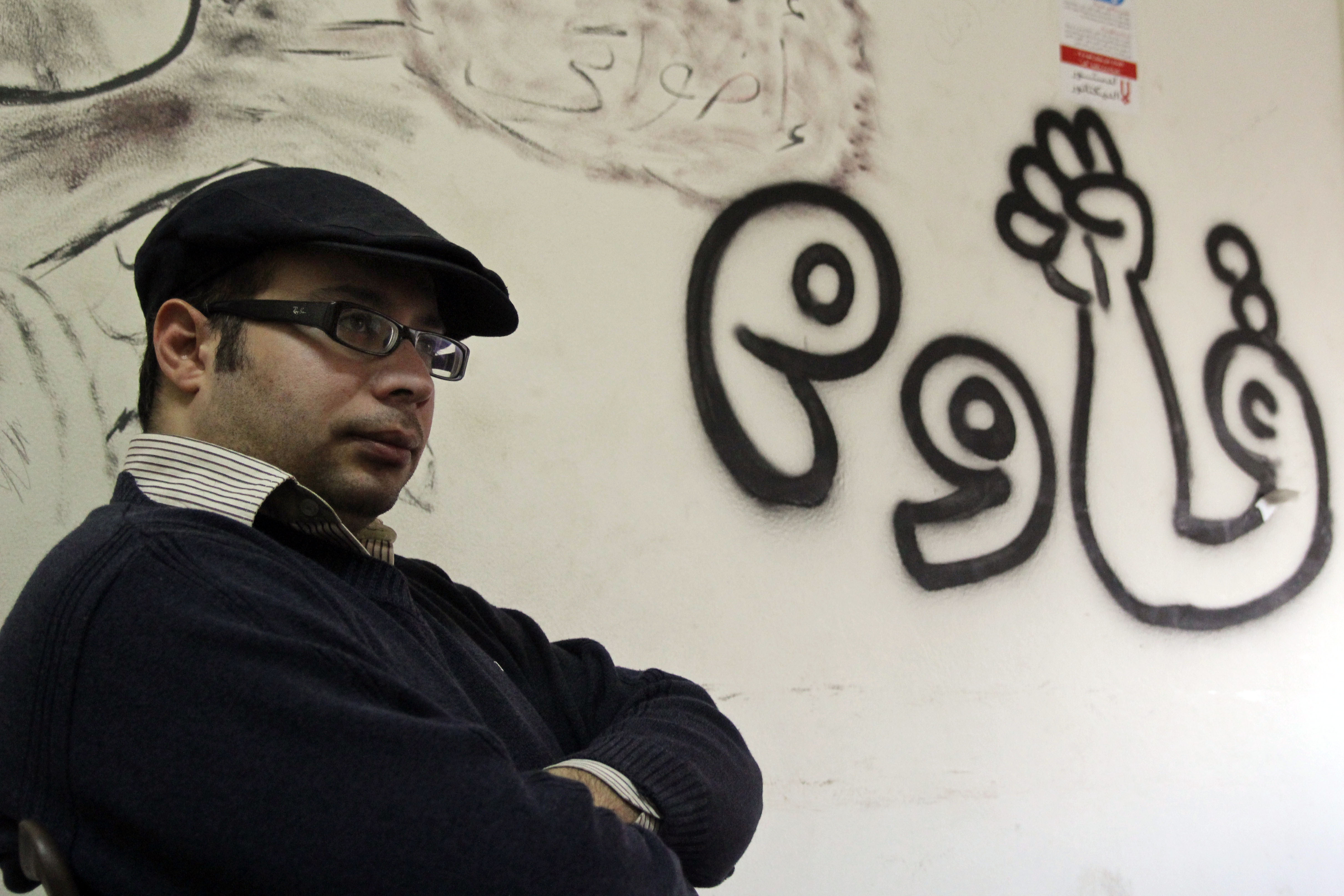 Ahmed Maher photographed in January 2013, in the headquarters of the April 6 Movement. The writing on the wall reads "resist." (Roger Anis/GroundTruth)