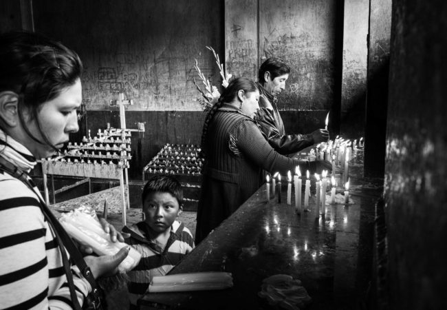 A family lights candles in a church after Mass on Sunday. The Catholic Church still has a strong presence, though most of the people are Quechua. (Alessandro Cinque/GroundTruth)