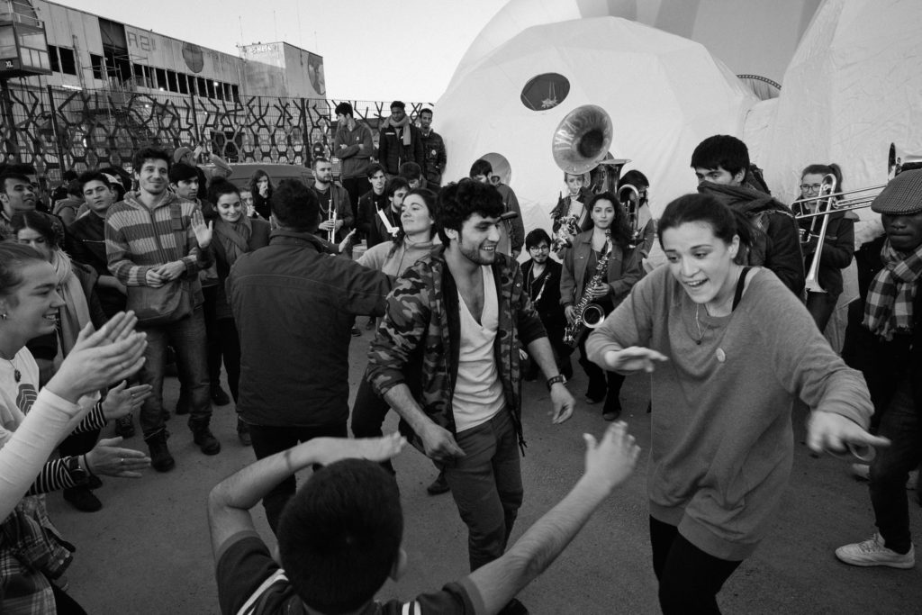 Brass band Tyrassonores led Hope Show attendees out of the Dome, starting a brief dance party to conclude the show. Zmary Zahyre (center left), an Afghan man residing at La Bulle, dances with Italian visiting curator Elisa Giovanetti (right) and a young boy. Elisa's role as visiting curator involved bringing in artists to lead workshops, but as with virtually everyone else involved in Good Chance, she also wore many other hats with less official titles. "My special skill is loving people," she replied, laughing. (Photo by Annabelle Marcovici/GroundTruth)