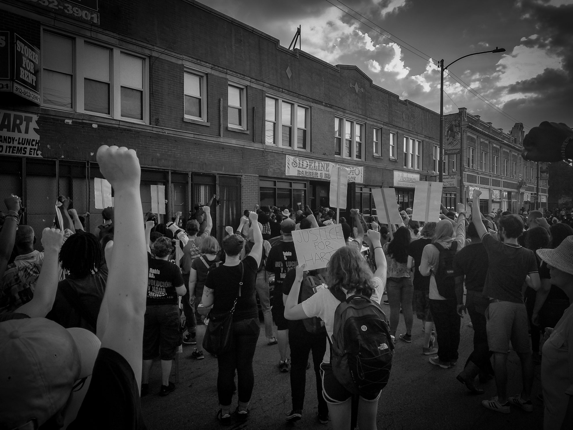 Protesters stand outside of Sideline Studio, the barber shop Harith "Snoop" Augustus worked at. (Photo by Manny Ramos/GroundTruth)