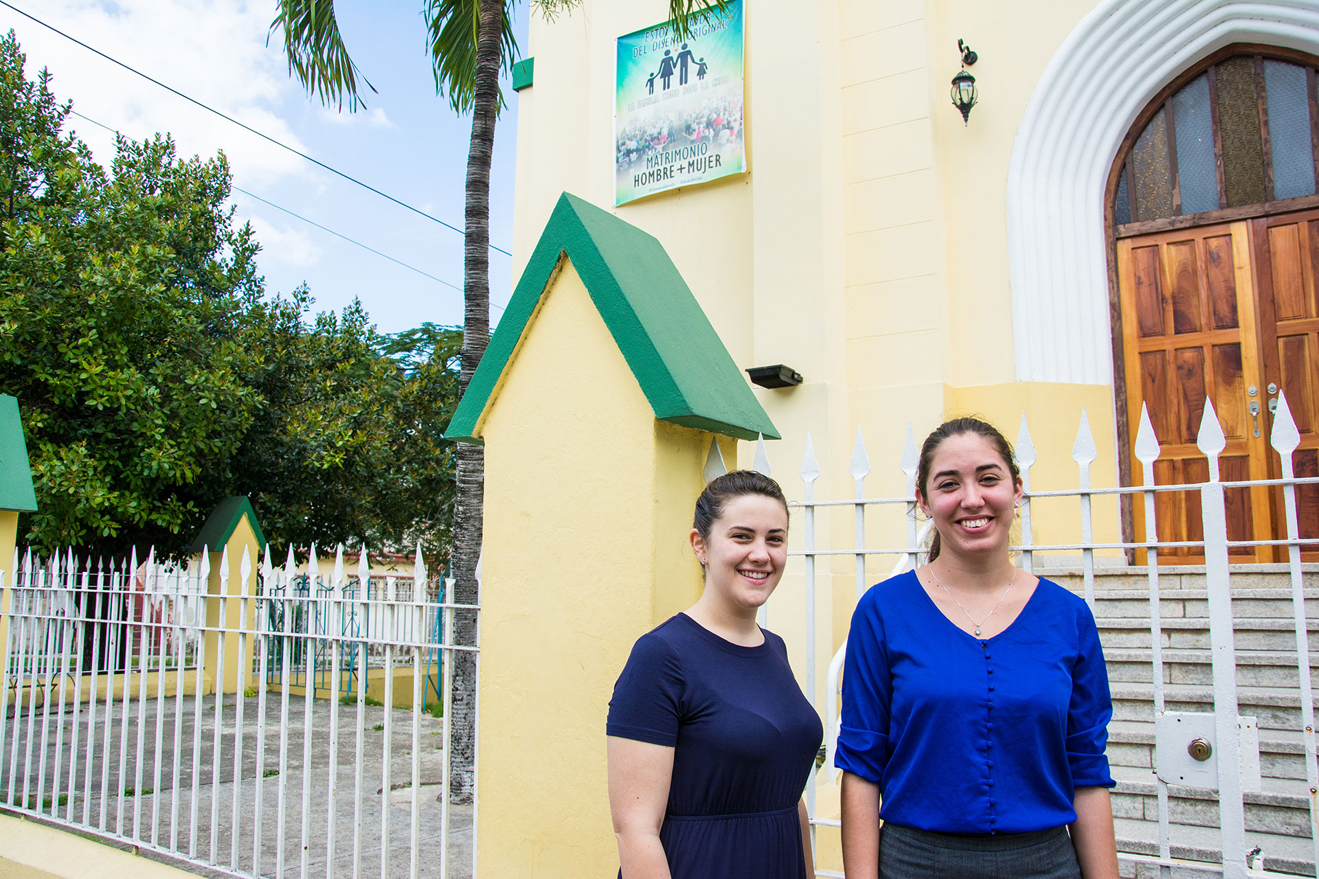 Danielle Byerly, left, a visiting missionary from Asheboro, North Carolina, and Pastor Leidy Guerra pose for a portrait March 9, 2019, outside of Iglesia Metodista de Marianao, their church in southwest Havana, Cuba. Evangelical churches across Cuba hung posters opposing the constitutional referendum and same-sex marriage with the phrase, “I am in favor of the original design.”  (Photo by Story Hinckley/GroundTruth)