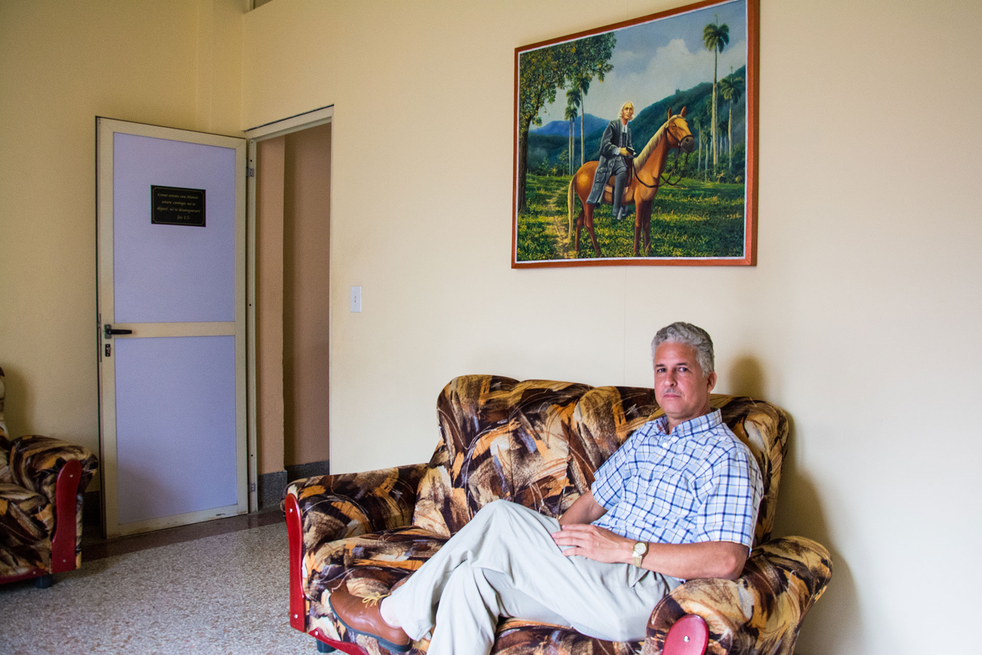 Rev. Enoel Gutierrez poses for a portrait March 6, 2019, at Seminario Evangelico Metodista in Havana, Cuba. Gutierrez commissioned a painting for his office of the Methodist leader from the 18th century, John Wesly, on horseback in Cuba. Rev. Gutierrez is part of the country's growing evangelical community. (Photo by Story Hinckley/GroundTruth)